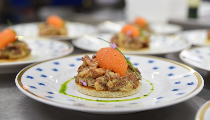 Tartine avec des girolles et des œufs d’ablette de Kalix sur une assiette blanche avec des couronnes bleues.